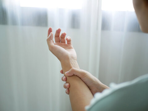 Asian business woman massaging wrist in pain caused by working on a computer keyboard for a long time, wrist pain and numbness in the wrist. While working at the office