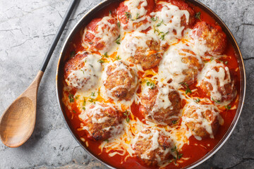 Baked cheesy meatballs casserole with tomato sauce in the oven dishn close-up on the table. Horizontal top view from above