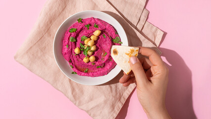 hand dipping pita bread in Beetroot hummus, top view