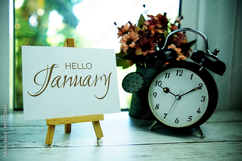 Poster hello january text on paper card with easel and alarm clock in the window background