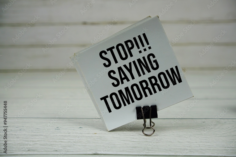 Poster stop saying tomorrow text message write on sticky note on wooden background