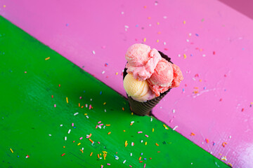 Artisanal ice cream of different flavors in a chocolate cone on a colorful table.