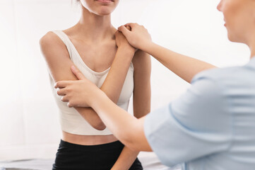 Fototapeta premium posture correction. Chiropractic, back pain relief. Professional female physical therapist doing shoulder, elbow and hand massage in hospital elbow