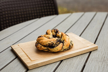 A poppyseed bun on a wooden board