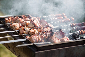 Pork kebab in the country in nature. May holidays. Pork kebab on skewers. The process of cooking meat on the grill with smoke, close-up.