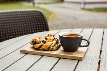 A freshly baked poppyseed bun and a cup of black coffee