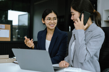 Business women write project ideas and use laptops to edit papers for brainstorming sessions with partners in the office.