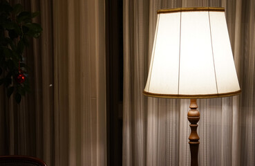 Desk lamp by the window with curtains in the room at night