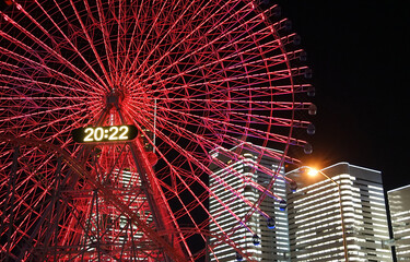 Scenery of skyscraper buildings and Ferris wheel illuminated at night in Yokohama City, Japan