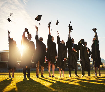University, graduation and people with cap in air for education goals, success and achievement. Happy, friends and students with celebration at campus field for learning, knowledge and qualification