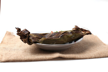 pepes ikan or fish wrapped in banana leaves with a mixture of traditional spices such as turmeric, onions, lemon grass, which are finely ground, and chopped tomatoes or chilies then steamed or grilled