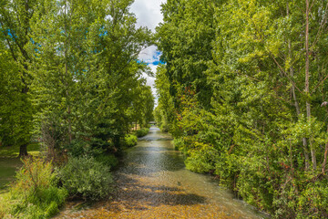 Tranquil view of the Arlanzon River surrounded by lush greenery in Burgos, Spain, on a sunny day