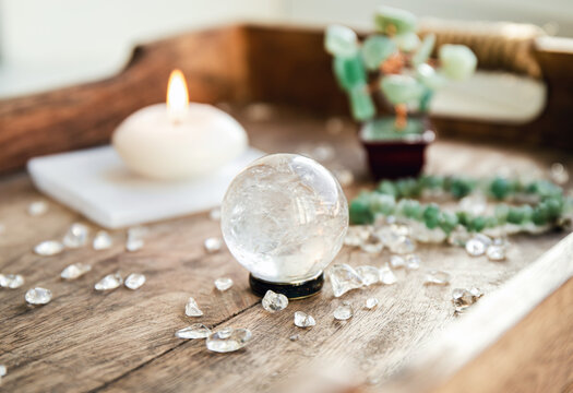 Gemstone crystal sphere or crystal balls known as crystallum orbis and orbuculum which is the beacon of peace and harmony in home environment. Natural clear quartz ball on stand on wood tray in home.