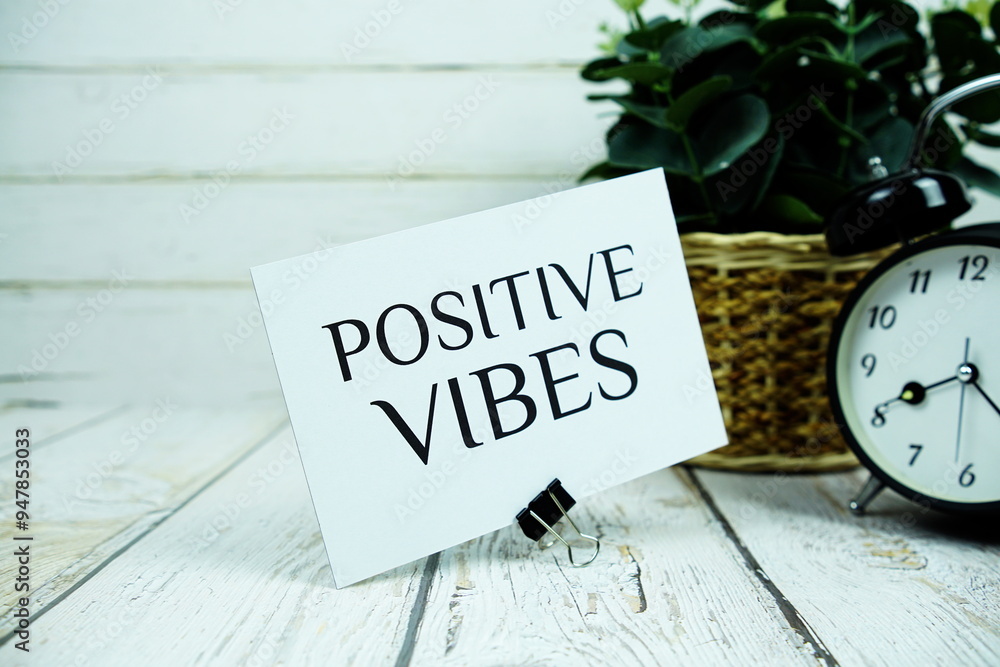 Poster inspirational quote positive vibes text message with alarm clock on wooden background