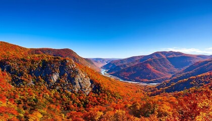 Fototapeta premium Stunning Autumn Landscape with Vibrant Fall Foliage and Serene River Flowing Through Majestic Mountains Under a Clear Blue Sky