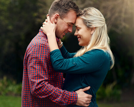 Hug, happy couple and forehead touch outdoor for love, commitment or marriage anniversary with eyes closed. Smile, man and woman embrace in nature on holiday date for support or romantic connection