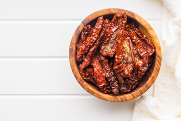 Sun dried red tomatoes in bowl on white table.