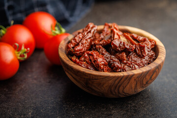Sun dried red tomatoes in bowl on black table.