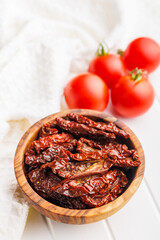 Sun dried red tomatoes in bowl on white table.