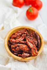 Sun dried red tomatoes in bowl on white table.