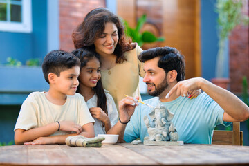 Indian family making eco-friendly Ganesh idol in outdoor garden for Ganesh Chaturthi celebration