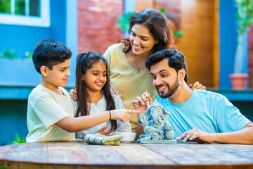 Indian family making eco-friendly Ganesh idol in outdoor garden for Ganesh Chaturthi celebration