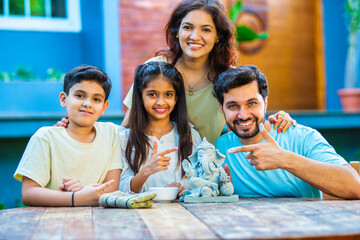Indian family making eco-friendly Ganesh idol in outdoor garden for Ganesh Chaturthi celebration