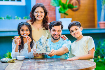 Indian family making eco-friendly Ganesh idol in outdoor garden for Ganesh Chaturthi celebration