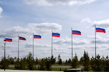Fototapeta premium Lots of Russian flags against the sky in the park on a summer day.