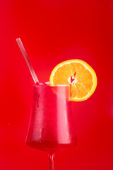 refreshing tropical cocktail glass of strawberry red fruits with orange slice close up