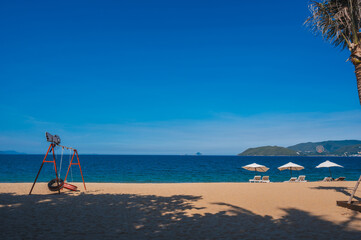 beach umbrellas with sun loungers without people on a sandy beach against the background of the sea.