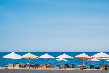 beach umbrellas with sun beds on a sandy beach against the background of the sea or ocean. Without people