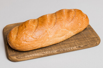 Freshly baked bread on cutting board against white wooden background. perspective view bread with copy space