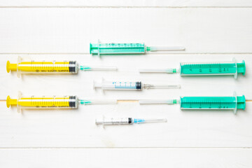 Top view of medical syringes with needles at wooden background with copy space. Injection treatment concept