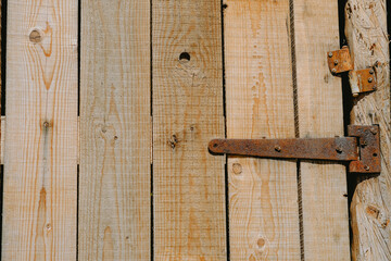 Close-up of rustic wooden door with rusted hinge showcasing natural wood grain and texture