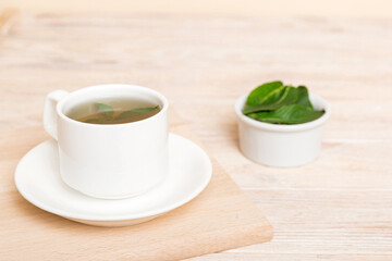Cup of mint tea on table background. Green tea with fresh mint top view with copy space