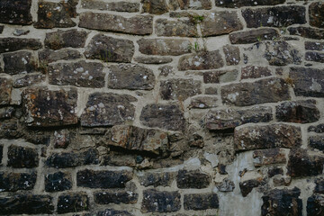 Weathered stone wall with varying textures and colors at an old building in a natural setting