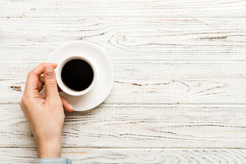 Minimalistic style woman hand holding a cup of coffee on Colored background. Flat lay, top view espresso cup. Empty place for text, copy space. Coffee addiction. Top view, flat lay