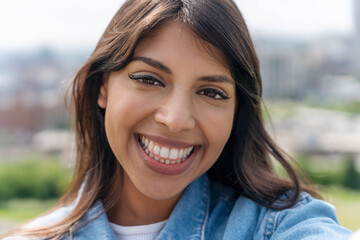 Joyful Woman Enjoying Sunny Outdoor View With Bright Smile in City Skyline Backdrop