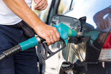The gas station. A man refuels a car with gasoline. A Russian fuel dispenser in the fuel tank of a car at a gas station. Rising fuel prices around the world.