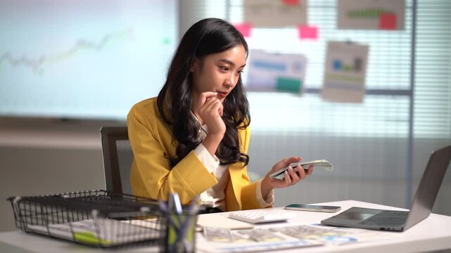 Asian businesses women working in the office used laptop and smartphone at her dest 