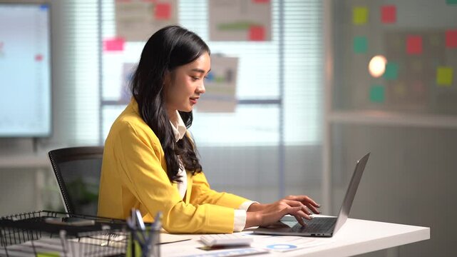 Asian businesses women working in the office used laptop and smartphone at her dest 