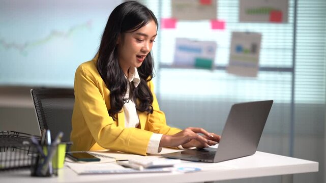 Asian businesses women working in the office used laptop and smartphone at her dest 