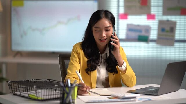 Asian businesses women working in the office used laptop and smartphone at her dest 
