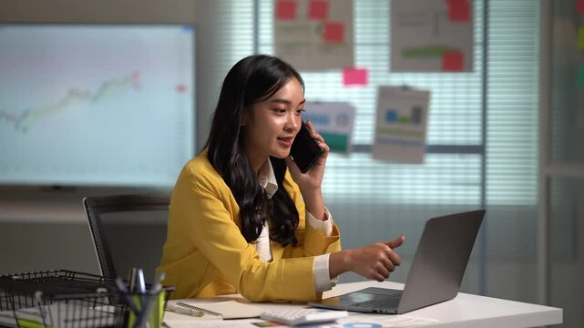 Asian businesses women working in the office used laptop and smartphone at her dest 