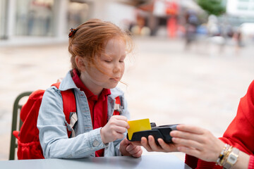 Young Girl Making a Payment While Enjoying a Sunny Day at a Vibrant Outdoor Market