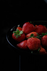 a bowl of red ripe strawberries on a dark background