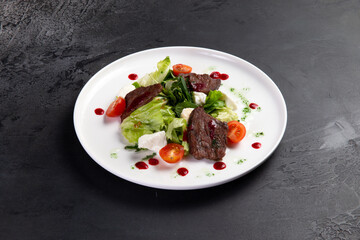 Beef salad in a plate. on a dark background.