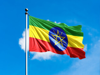 Ethiopia flag flying on blur blue clouds background.