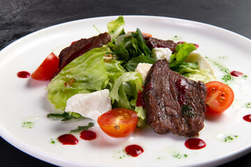 Beef salad in a plate. on a dark background.